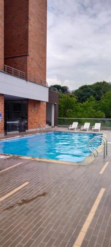 una gran piscina con sillas y un edificio en Habitación en apartamento familiar en Medellín