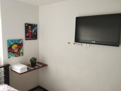 Habitación con TV de pantalla plana en la pared en Habitación en apartamento familiar en Medellín