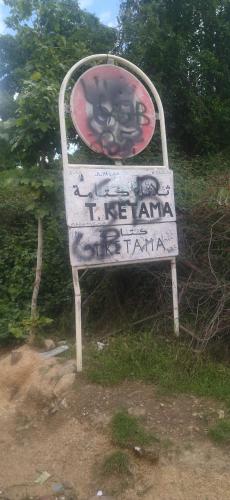 a sign with graffiti on it in the grass at Ketama house in Ketama