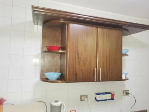 eine Küche mit Holzschränken mit Schalen darauf in der Unterkunft فيلا مكيفة بجاردن ورووف بالنجيل الصناعى وبرجولا in Dawwār ‘Abd Allāh