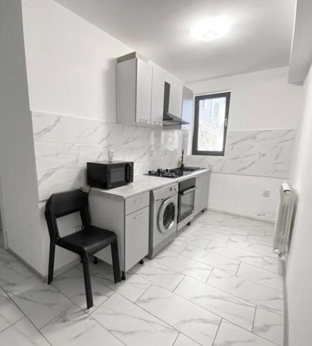 a kitchen with a washing machine and a chair in it at City Center Apartment in Tulcea