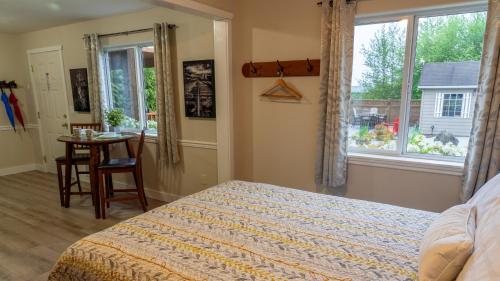 a bedroom with a bed and a table and a window at Wild Pacific Guest Suites in Ucluelet