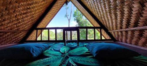 a room with a large window and a bed in a tree house at Second Home Bungalows in Tetebatu