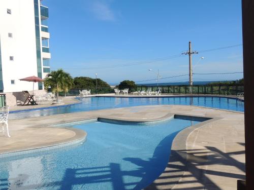 a large swimming pool with blue water in a building at Apartamento Luxo em Arraial do Cabo- RJ in Arraial do Cabo