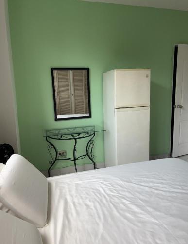 a bedroom with a white bed and a refrigerator at Habitación amplia con baño privado en Apartamento familiar in Panama City