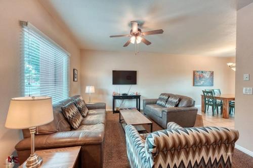 a living room with couches and a ceiling fan at 3BR / 2BA Townhome with Pool, Patio, WiFi, Washer/Dryer in Kanab