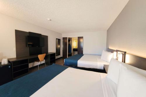 a hotel room with two beds and a flat screen tv at Motel 6-Anaheim, CA - Maingate in Anaheim