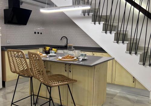 een keuken met een aanrecht met stoelen en een trap bij Apartamento Centro Cabildo Antiguo Convento in Sanlúcar de Barrameda