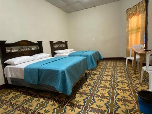 1 dormitorio con 2 camas con sábanas azules y alfombra en Hotel Malybu en Guatemala