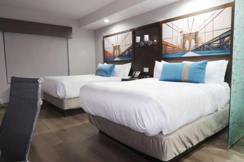 a hotel room with two beds with white and blue pillows at Hotel Manhattan, BW Signature Collection in New Caney
