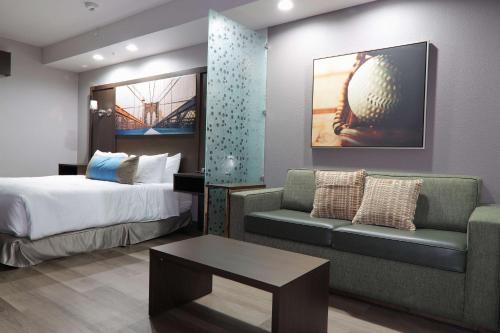 a hotel room with a bed and a couch at Hotel Manhattan, BW Signature Collection in New Caney