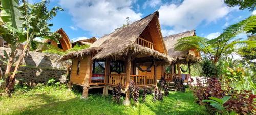 a house with a thatched roof in the grass at Second Home Bungalows in Tetebatu