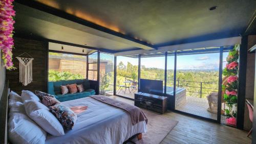 Schlafzimmer mit einem Bett und einem Balkon mit einem TV in der Unterkunft Cumbres Luxury Glamping in Guarne