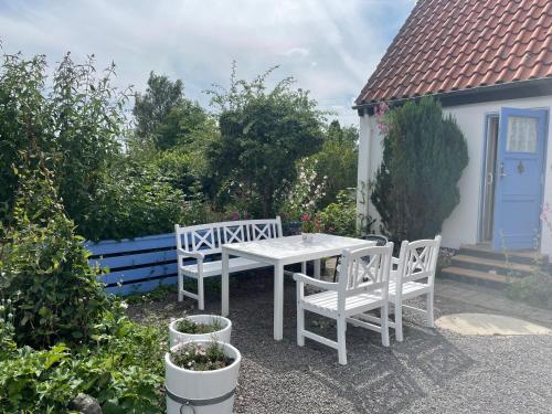 einen weißen Tisch und zwei Stühle in einem Garten in der Unterkunft ØsterLars blue Pearl in Gudhjem