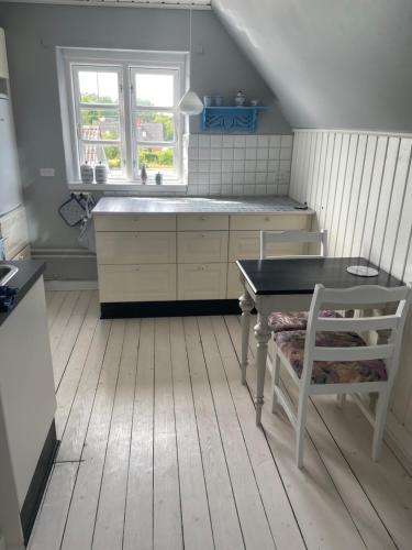 eine Küche mit einem Waschbecken, einem Tisch und einem Stuhl in der Unterkunft ØsterLars blue Pearl in Gudhjem