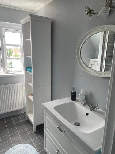 ein weißes Badezimmer mit einem Waschbecken und einem Spiegel in der Unterkunft ØsterLars blue Pearl in Gudhjem