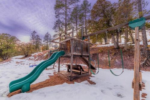 a playground with a green slide in the snow at Cabin#2 Elk Hallow - Pet Friendly - Sleeps 6 - Playground & Game Room in Payson