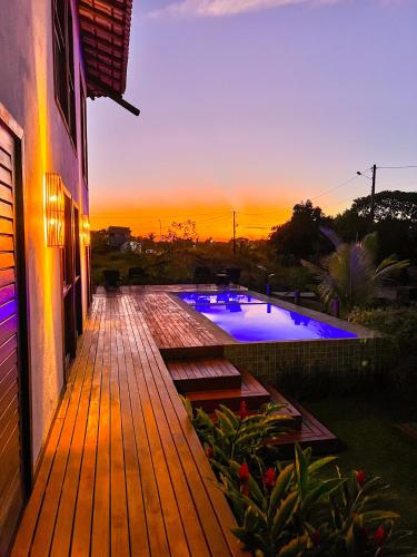 a wooden deck with a swimming pool at sunset at Oceà Privilegi - Taipu de Fora in Barra Grande