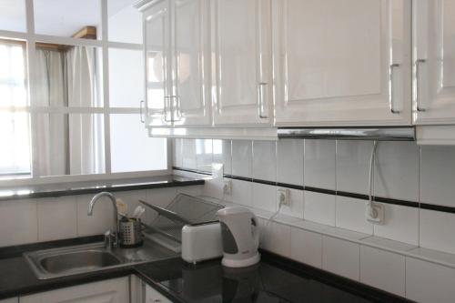 una cucina con armadi bianchi e lavandino di Campo Grande Residence a Lisbona