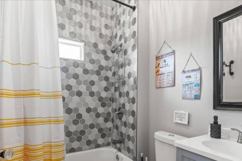 een badkamer met een douchegordijn en een wastafel bij BeeKeeper's Inn - Beautifully Renovated 1929 Bungalow with 2 Bedrooms on Brick Street near Tampa's Attractions in Tampa