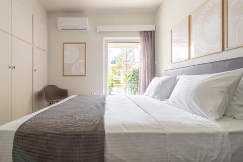 a bedroom with a large white bed with a window at Sea View Stylish Penthouse in Varkiza in Vari