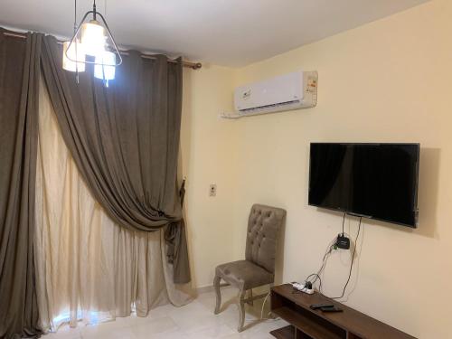 um quarto com uma cadeira e uma televisão na parede em Quiet and comfortable place in Madinaty new cairo em Madinaty