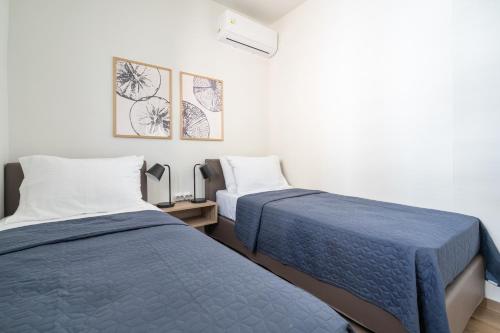 two beds in a room with white walls at Sea View Stylish Penthouse in Varkiza in Vari