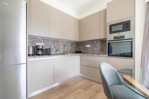 a kitchen with white cabinets and a glass table at Sea View Stylish Penthouse in Varkiza in Vari