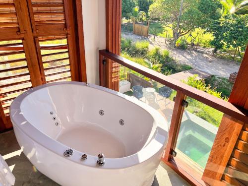 a large white bath tub in a room with a window at Oceà Privilegi - Taipu de Fora in Barra Grande