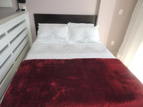 a bedroom with a bed with a red blanket on it at Loft Com Vista Para O Mar in Arraial do Cabo