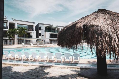 a swimming pool with chairs and a straw umbrella at Encantador Apartamento Ciudadela in Santa Fe de Antioquia