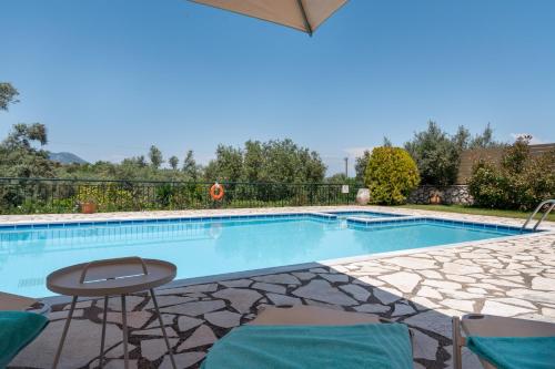 a swimming pool with a table and chairs next to it at Villa Eleni in Meganisi