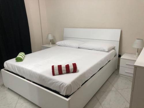 a white bed with a red and white tie on it at House Volla in Volla