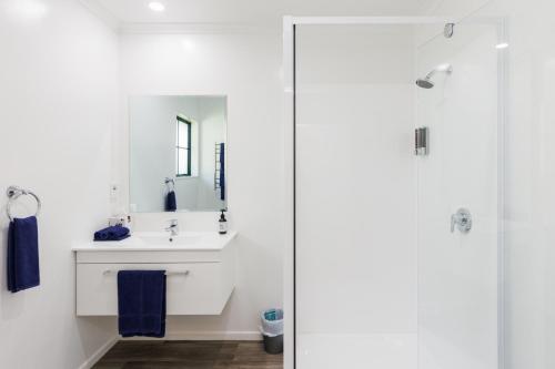 a white bathroom with a sink and a shower at Camelot Motor Lodge and Conference Centre in Palmerston North