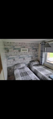 a bedroom with three beds against a brick wall at California beachhut chalet in Great Yarmouth