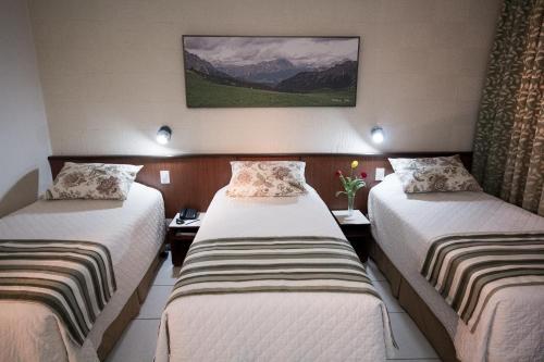 a hotel room with two beds and a picture on the wall at Aguas do Iguaçu Hotel Centro in Foz do Iguaçu