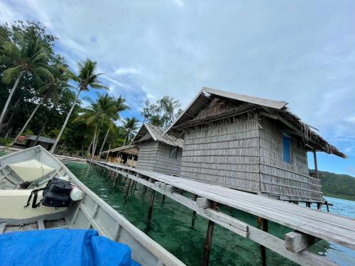 a house on a dock next to the water with a boat at Kri guest homestay in Rancakole