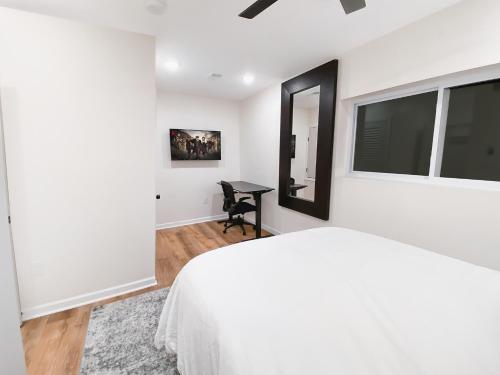 a white bedroom with a bed and a mirror at Rivera Properties in Washington, D.C.