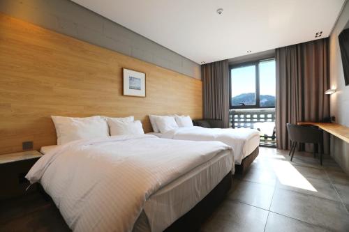 a hotel room with two beds and a balcony at The Hong C Hotel in Gangneung