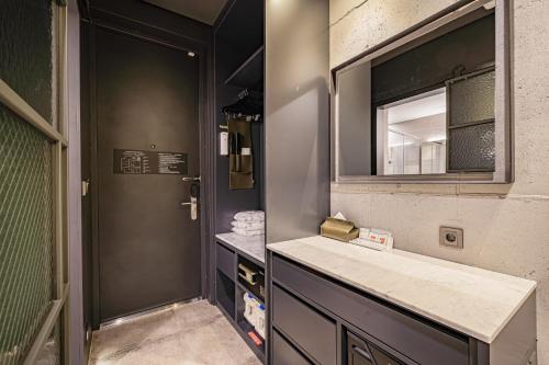 ein Bad mit einem Waschbecken und einem Spiegel in der Unterkunft The Hong C Hotel in Gangneung