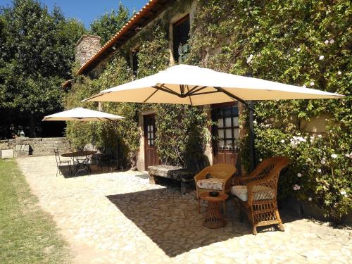 een patio met 2 stoelen en een parasol bij Douro Villa with Private Pool in Armamar