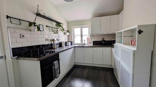 a kitchen with white cabinets and a black stove top oven at Converted Railway Cottage in Swindon
