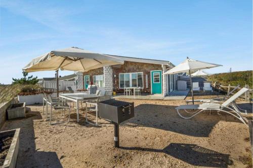 ein Haus mit 2 Sonnenschirmen, einem Tisch und Stühlen in der Unterkunft Driftwood Resort on the Ocean in Montauk