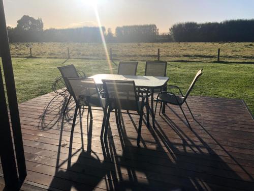a table and chairs on a deck with a field at Cute Cottage Close to Town in Hastings