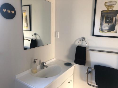 a white bathroom with a sink and a mirror at Cute Cottage Close to Town in Hastings