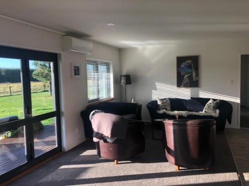 a living room with two leather chairs and a sliding glass door at Cute Cottage Close to Town in Hastings