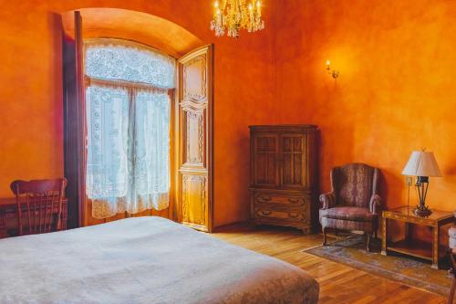 a bedroom with a bed and a chair and a window at La Casa de la Marquesa in Querétaro