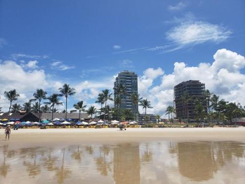 uma praia com guarda-sóis e edifícios ao fundo em Village Praia Dourada - Praia dos Milionários em Ilhéus