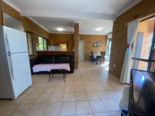 a living room with a couch and a refrigerator at Cosy holiday entire unit 1 in Caloundra West
