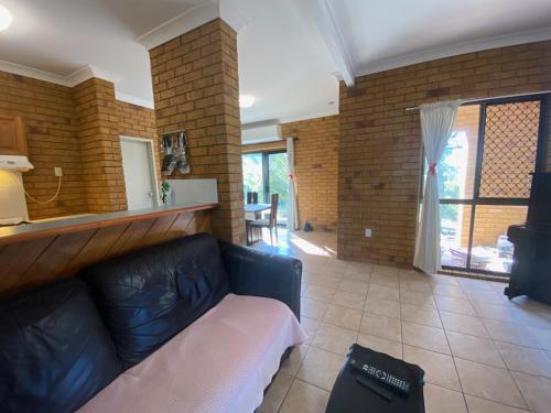 a living room with a black couch and a brick wall at Cosy holiday entire unit 1 in Caloundra West